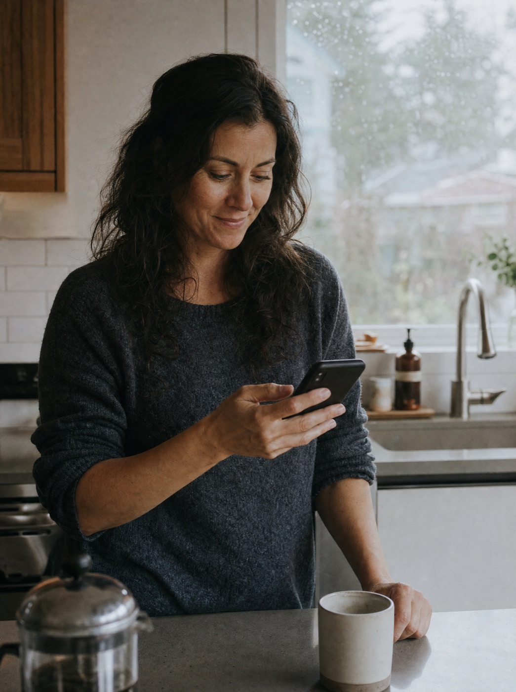 A daughter reading a text in her kitchen